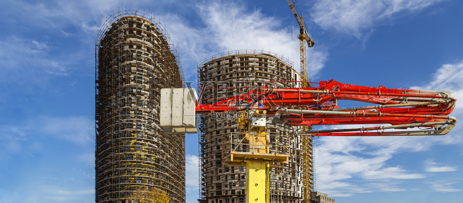 在俄罗斯莫斯科，混凝土泵(泵车)与多层建筑正在建设的背景与脚手架(新的住宅综合体)照片摄影图片