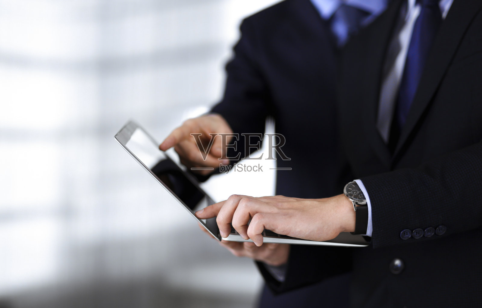 商务人士在会议上讨论演示，站在一个现代化的办公室里。一个不知名的商人和一个同事在电脑上搜索一些信息，律师在谈判。团队合作和伙伴关系概念照片摄影图片