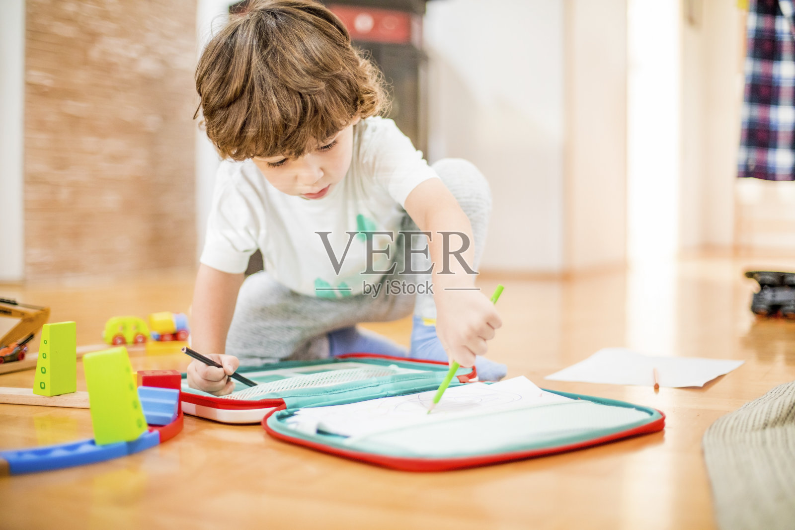 漂亮的学步男孩用纸和蜡笔画画。照片摄影图片