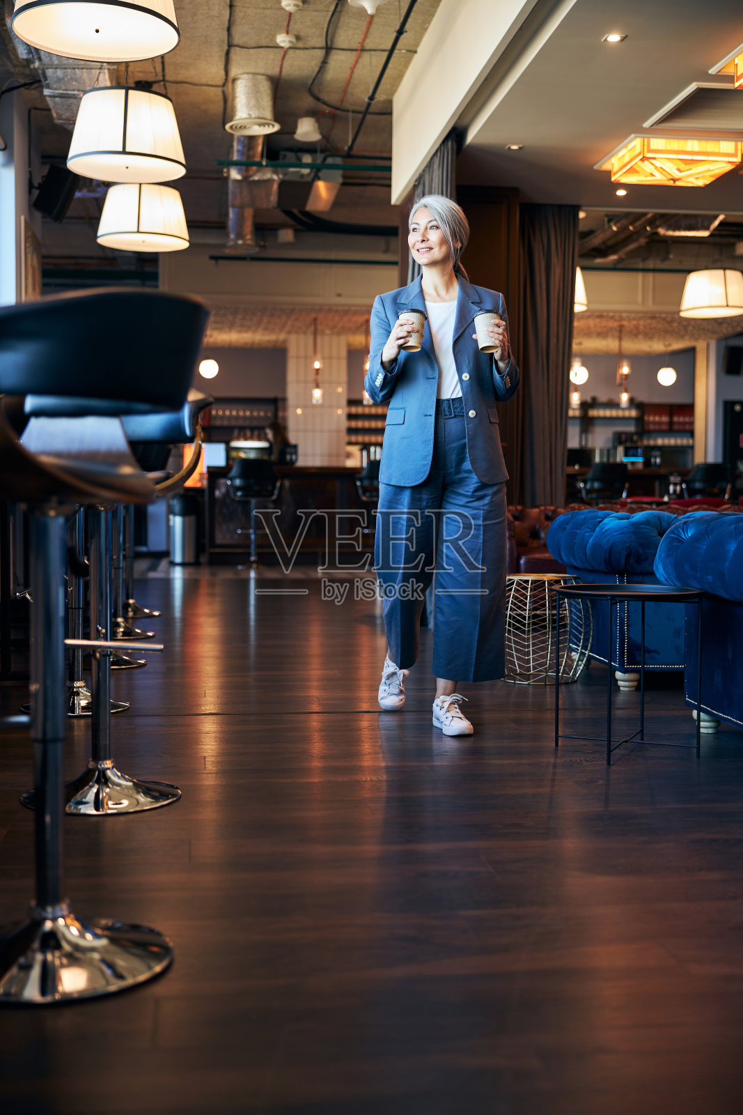 美丽快乐的女人拿着咖啡走在咖啡馆里照片摄影图片