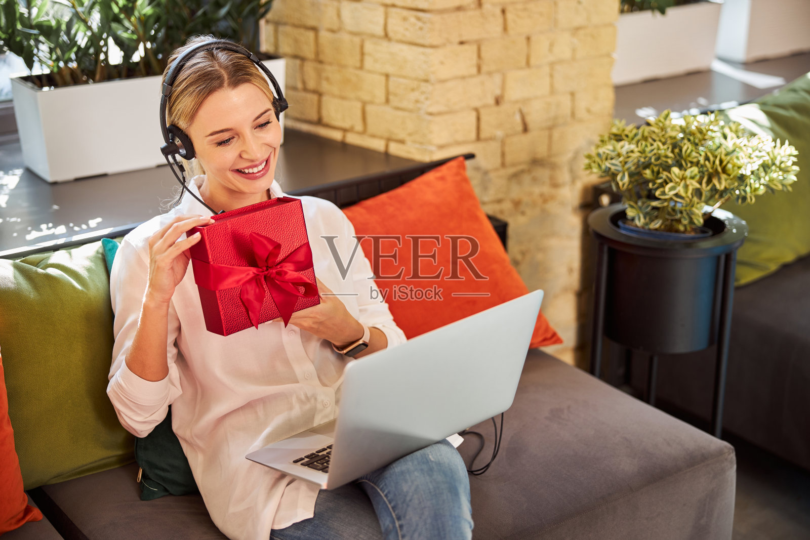 戴着耳机在笔记本电脑上上网聊天的漂亮女士照片摄影图片