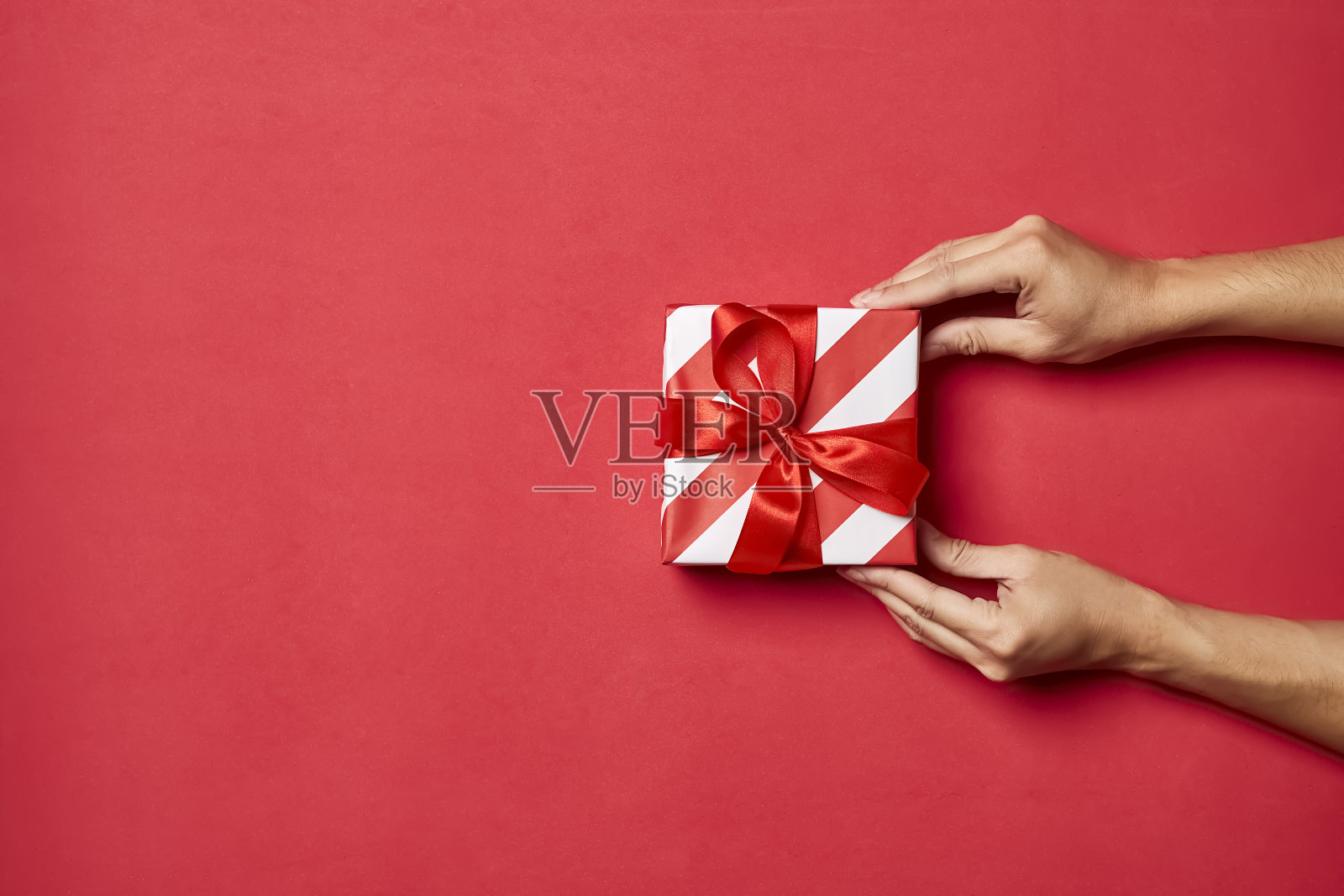 手送圣诞礼盒，圣诞球饰品红色背景顶部平面布局空白文本复制空间。照片摄影图片