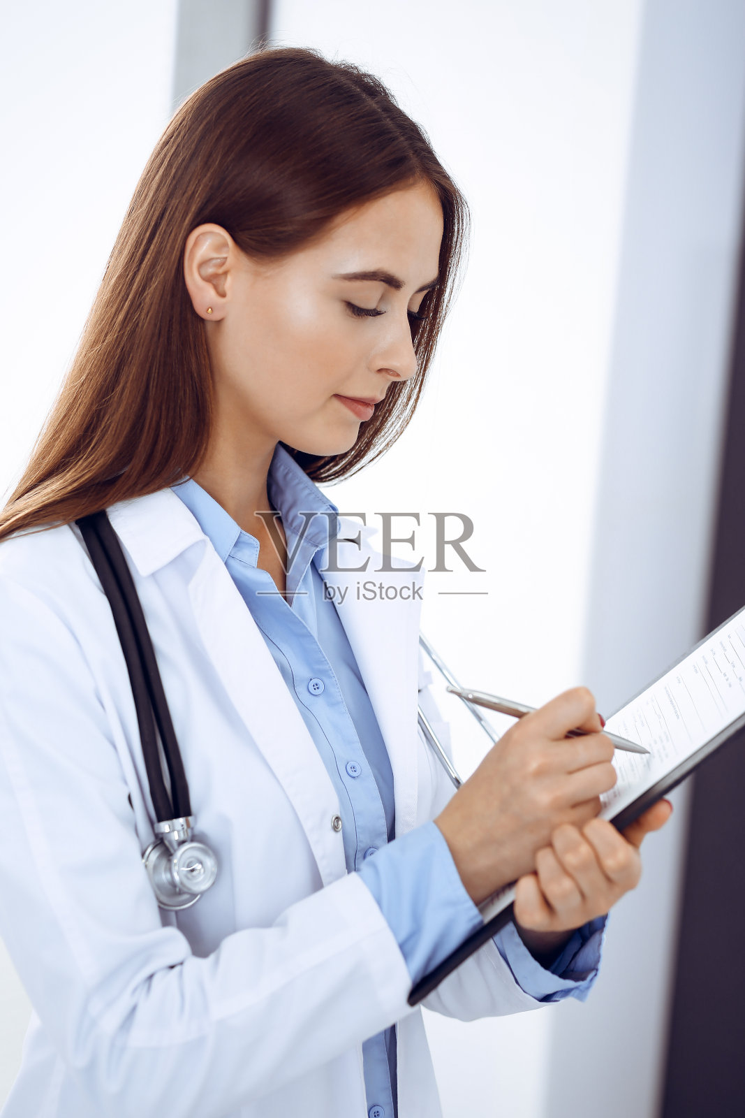 女医生站在诊所窗边填写医疗表格。医生在工作中。医学保健理念照片摄影图片