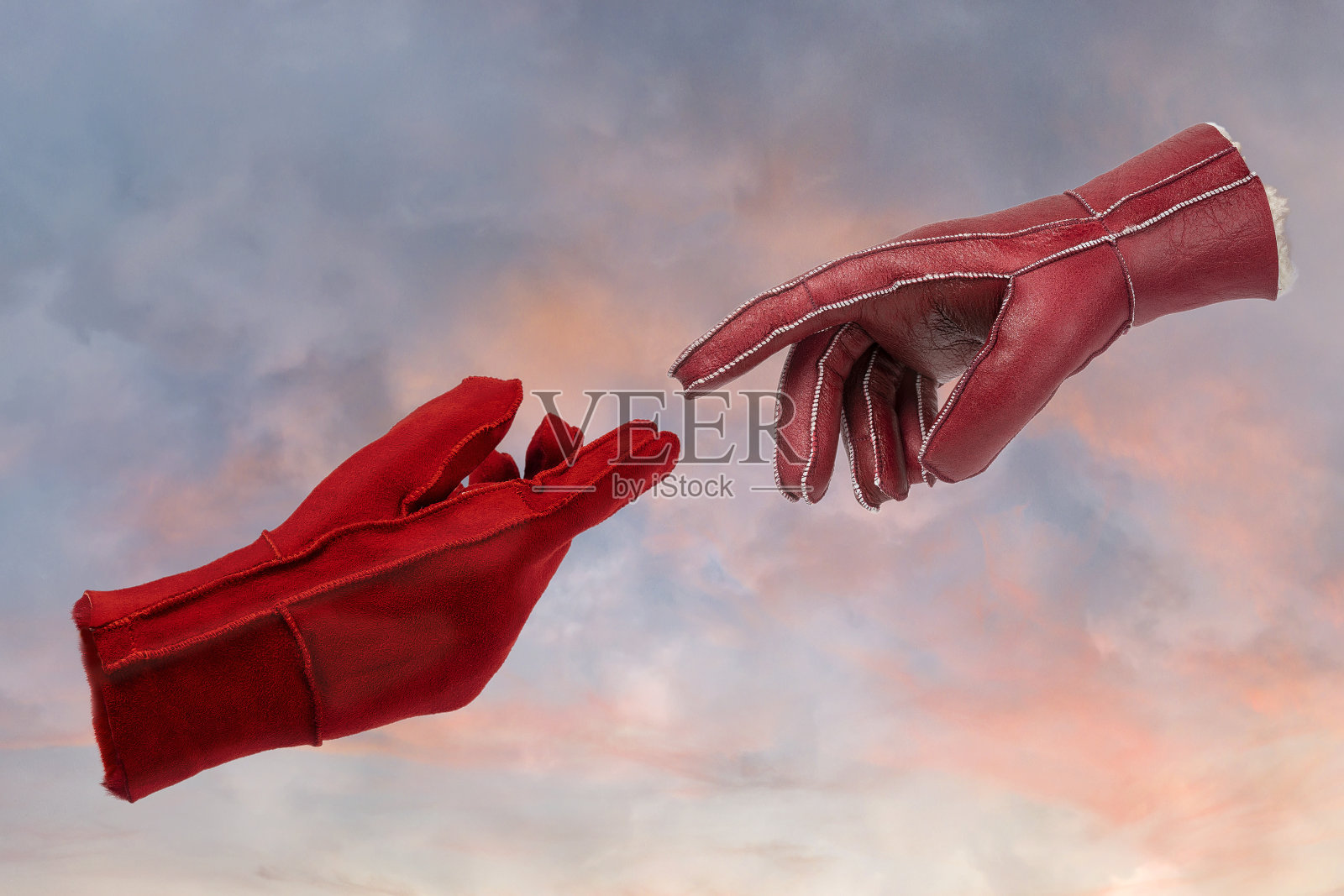 两只皮手套与手指接触在天空背景上。抽象艺术的概念。照片摄影图片