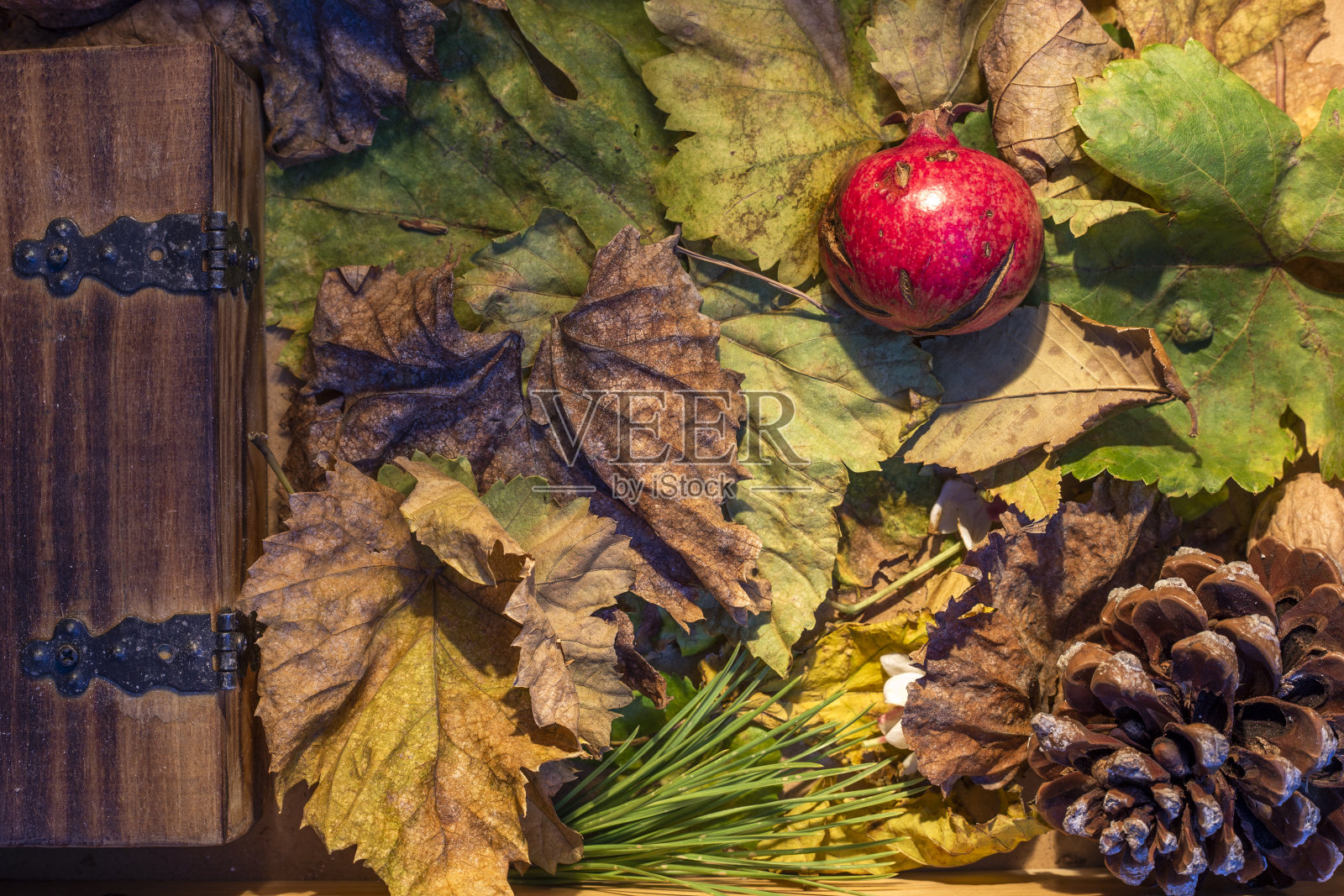 秋天的背景。木盒干叶，干石榴，干松果，松果叶，果仁照片摄影图片