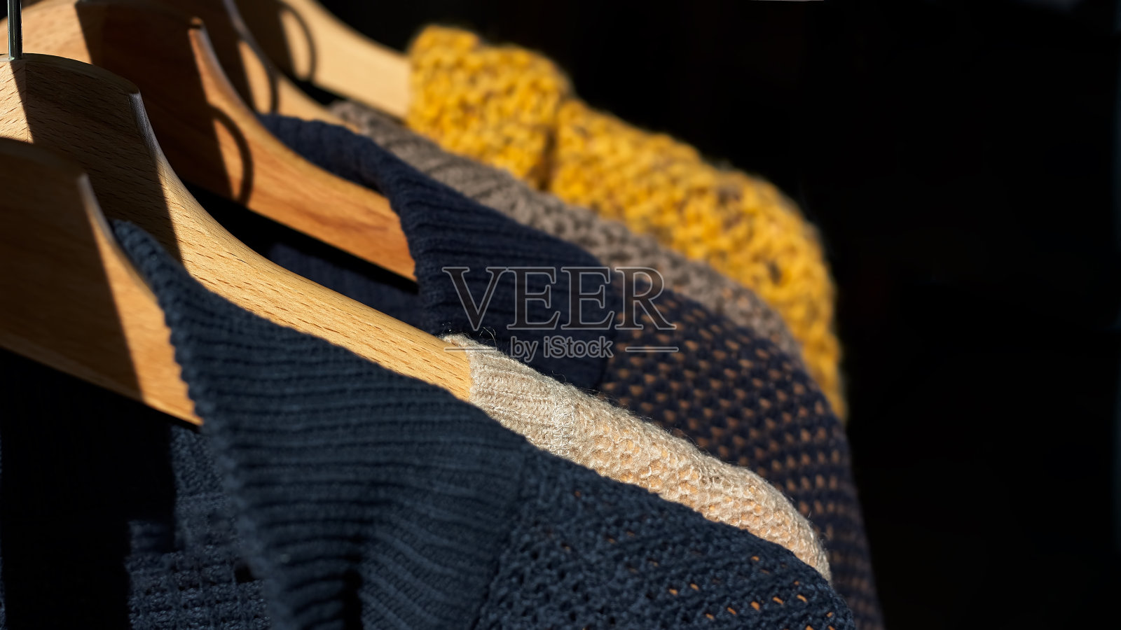 秋冬季节针织品。有不同针织图案的彩色暖针织毛衣挂在衣架上照片摄影图片