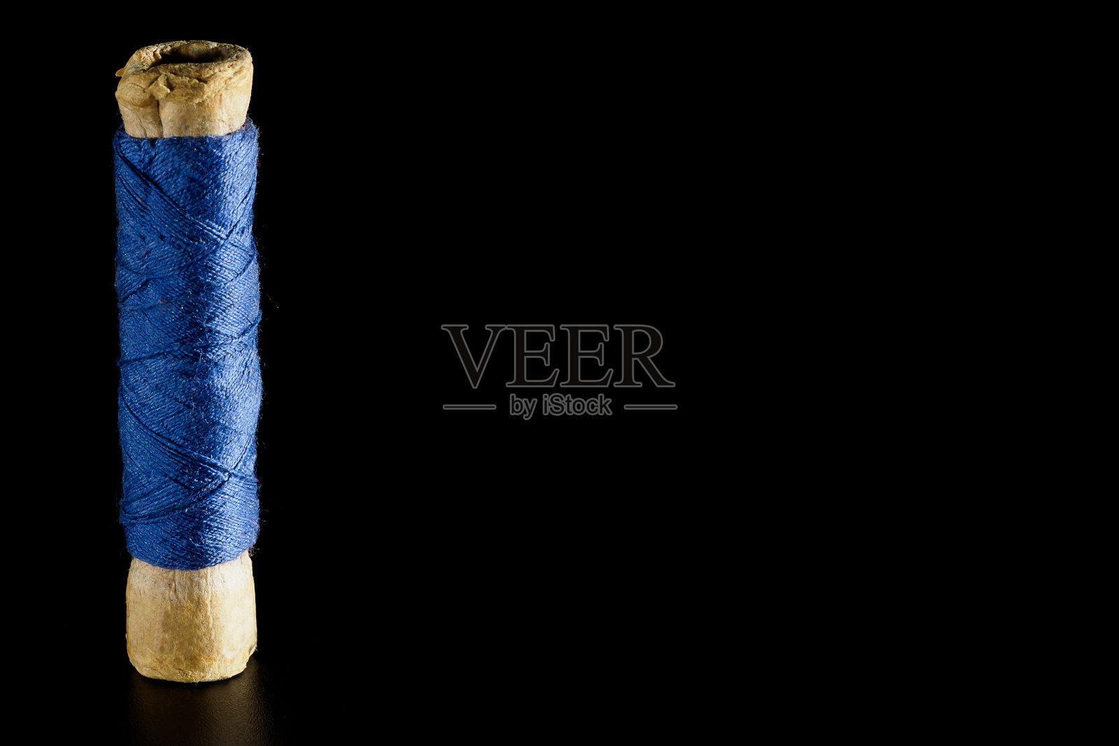 卷轴与蓝色缝纫丝线孤立在黑色背景，特写，复制空间。为缝纫和针线活提供明亮的背景照片摄影图片