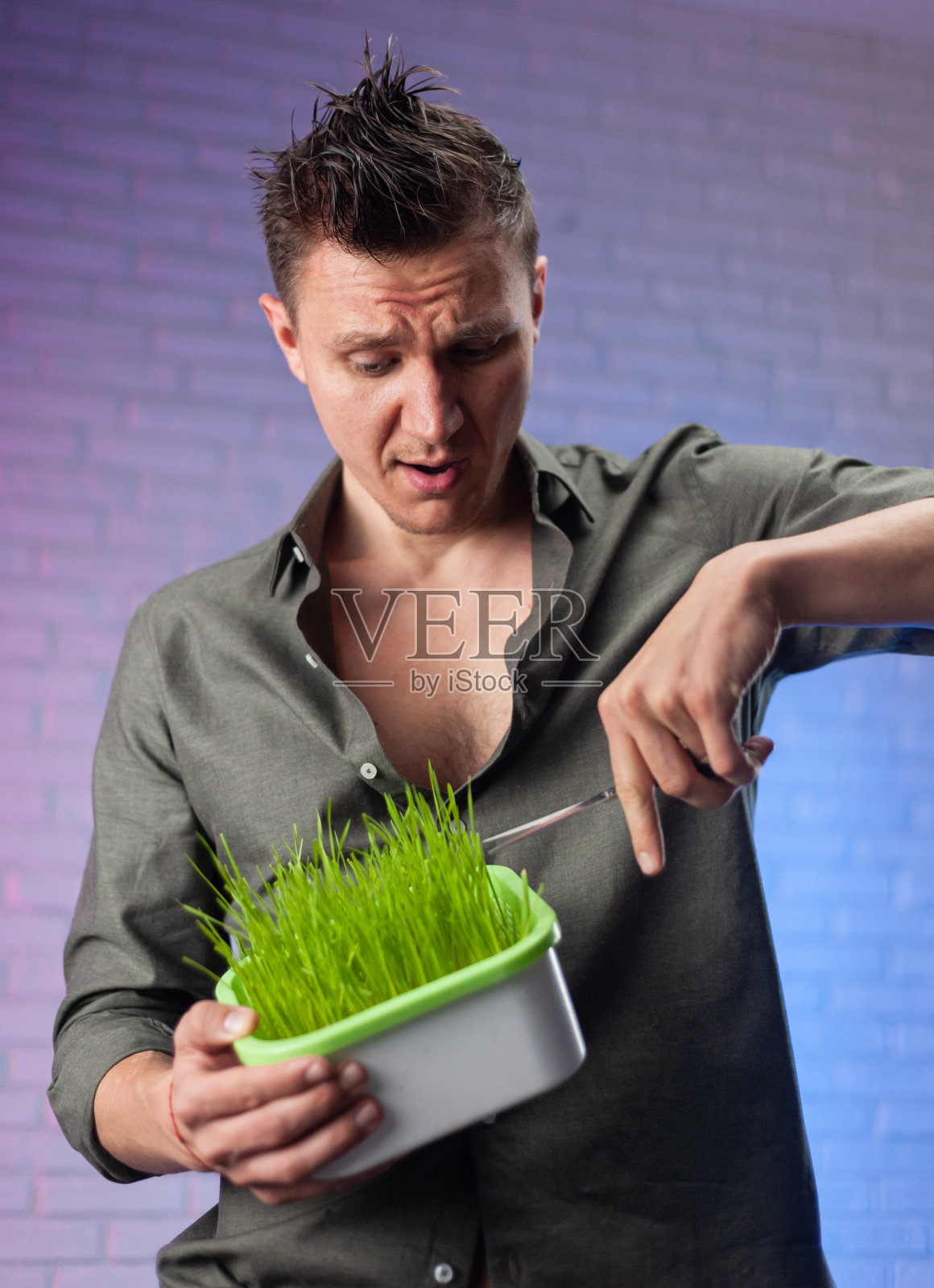 一个男人拿着一个种子发芽器，里面有正在生长的绿小麦和剪刀照片摄影图片