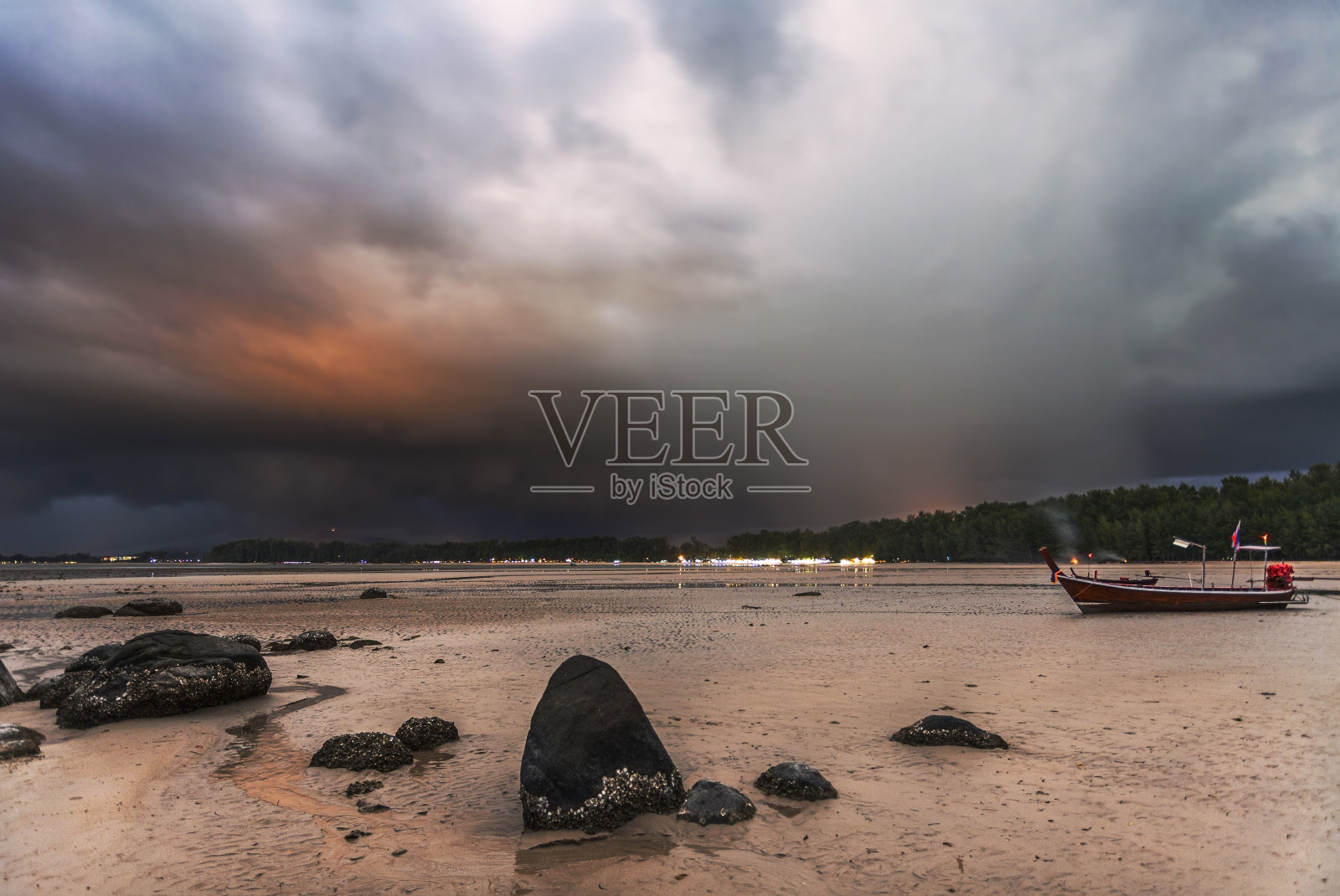 潮汐下的大海，在戏剧性的日落天空下照片摄影图片