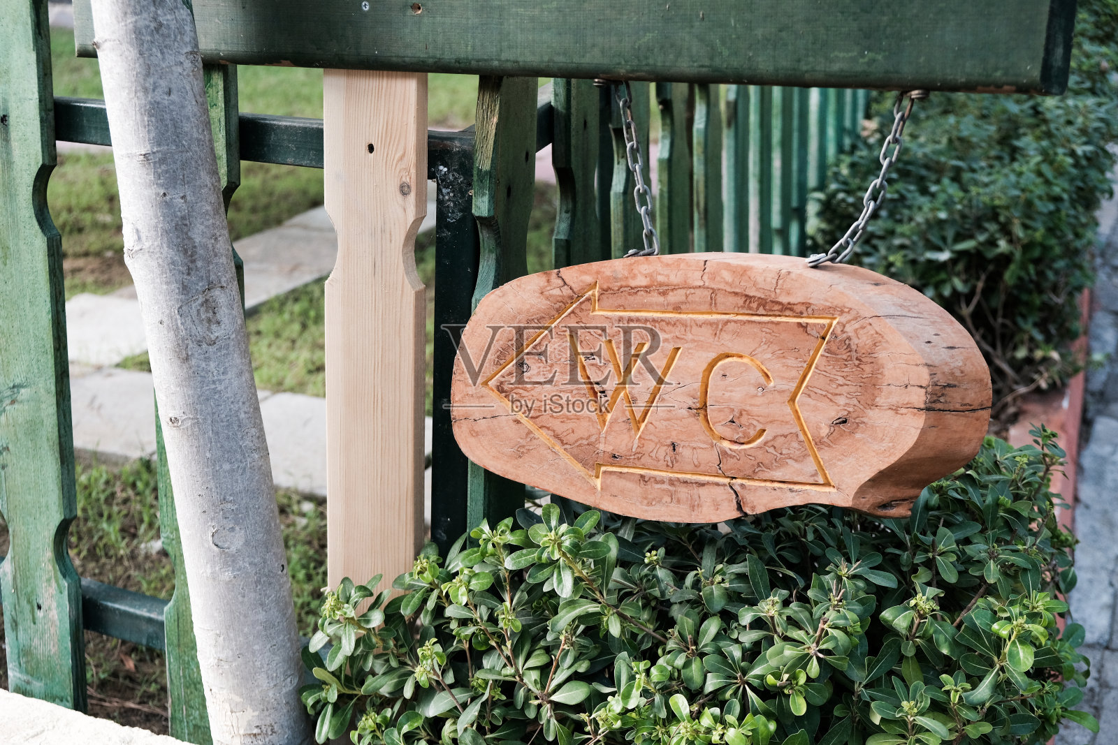 棕色木板上刻有WC标志和箭头，指示公共浴室的方向。照片摄影图片