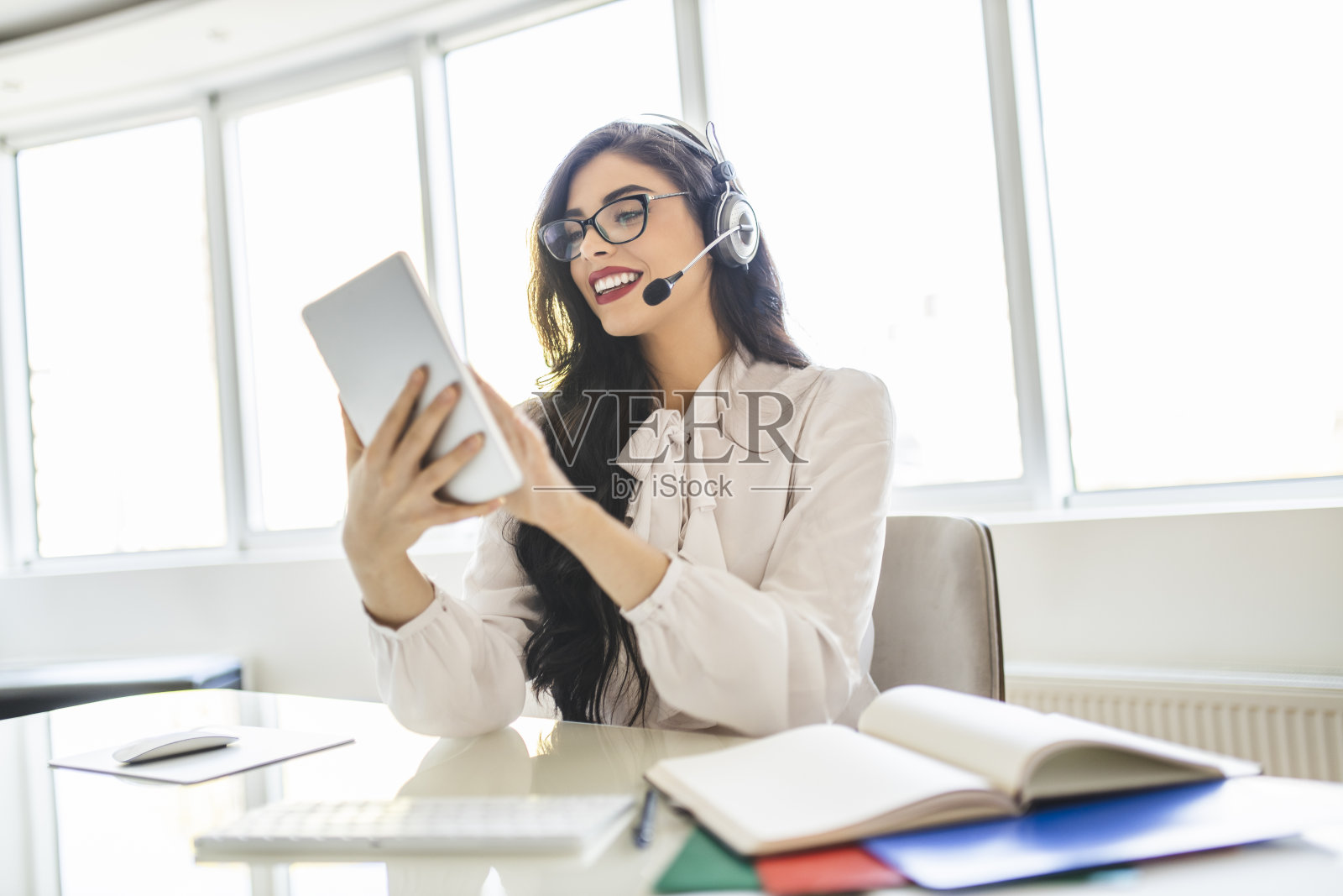 女智能教授戴着耳机，使用数字平板电脑，进行视频通话，为在线学习的学校孩子和学生举行在线课堂照片摄影图片