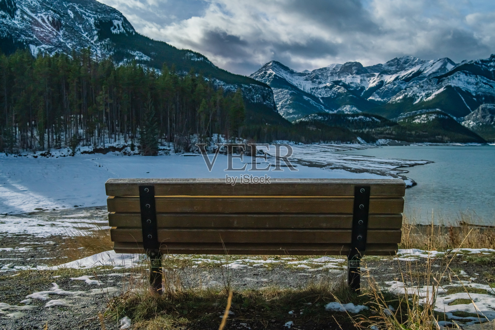 公园长椅俯瞰一个湖，背景是山脉照片摄影图片