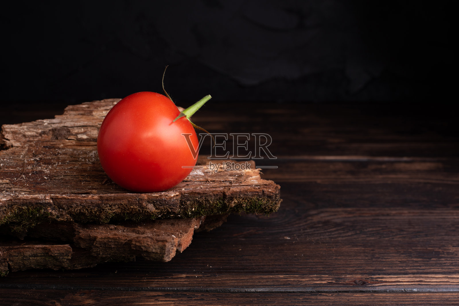 木桌和深色背景上放着一个新鲜的番茄照片摄影图片