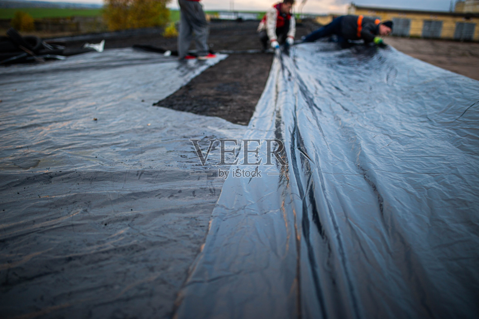 屋顶防水。建筑施工。屋顶上涂了一层防水薄膜。安装防水层。施工工程。照片摄影图片