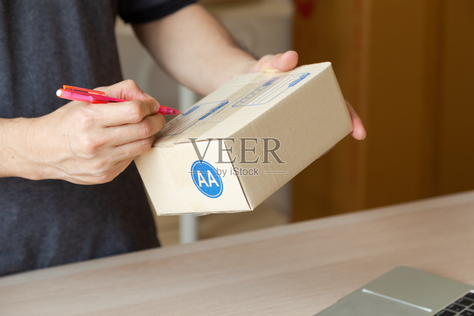 关闭商人为客户在盒子上写地址。在家工作和网上购物的概念。照片摄影图片