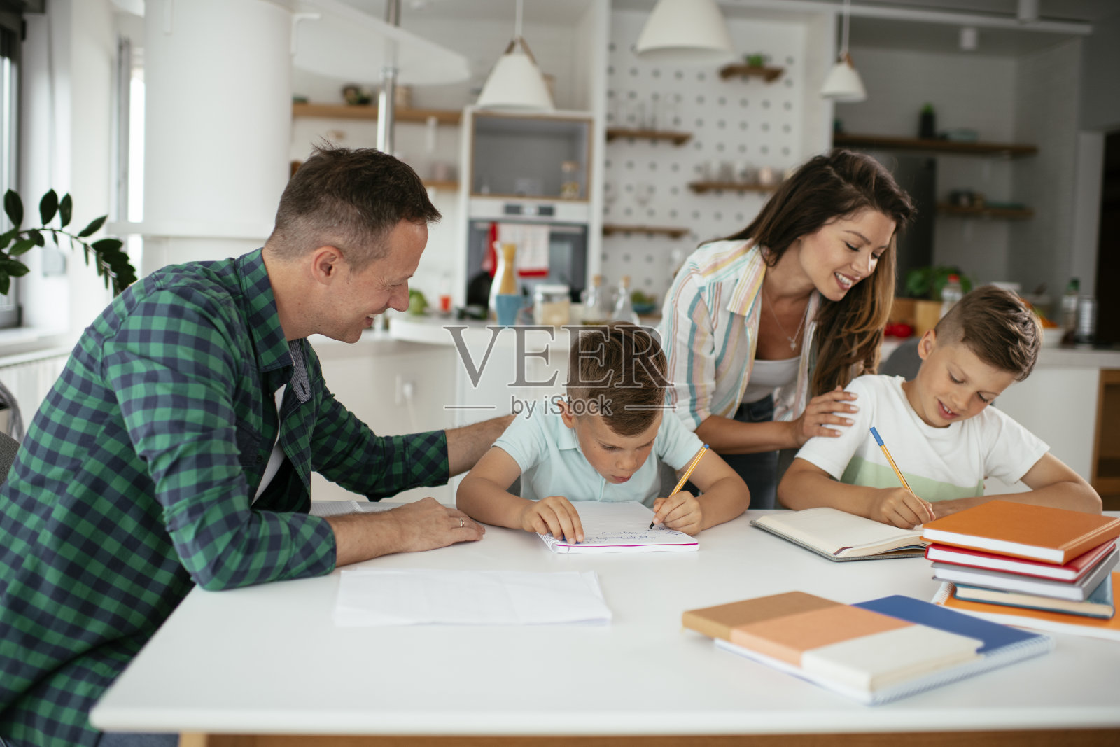 父母帮助孩子们做作业。照片摄影图片