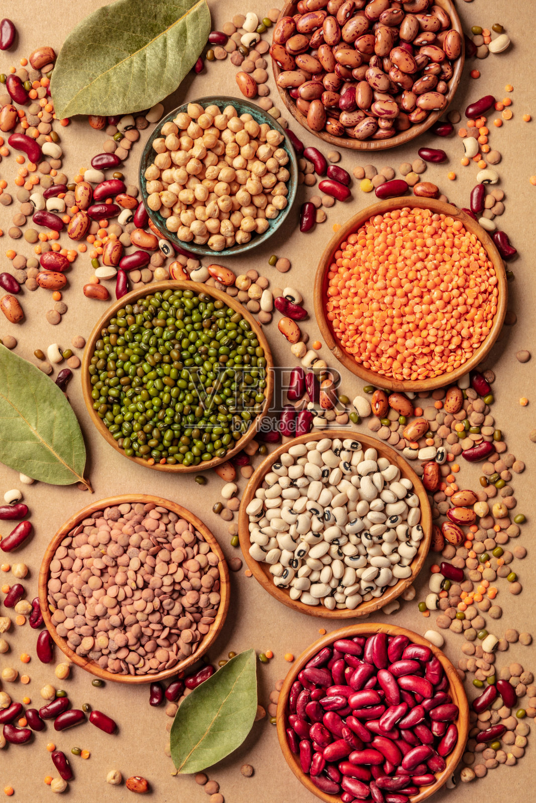 各种豆类，顶部拍摄在棕色背景上。扁豆、黄豆、鹰嘴豆、红芸豆等豆类，平铺一层照片摄影图片