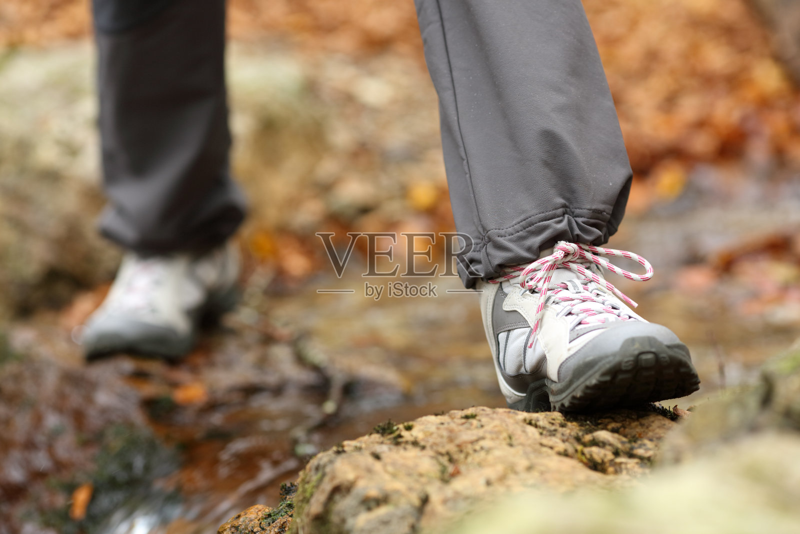 秋天，徒步者脚穿靴子过河照片摄影图片