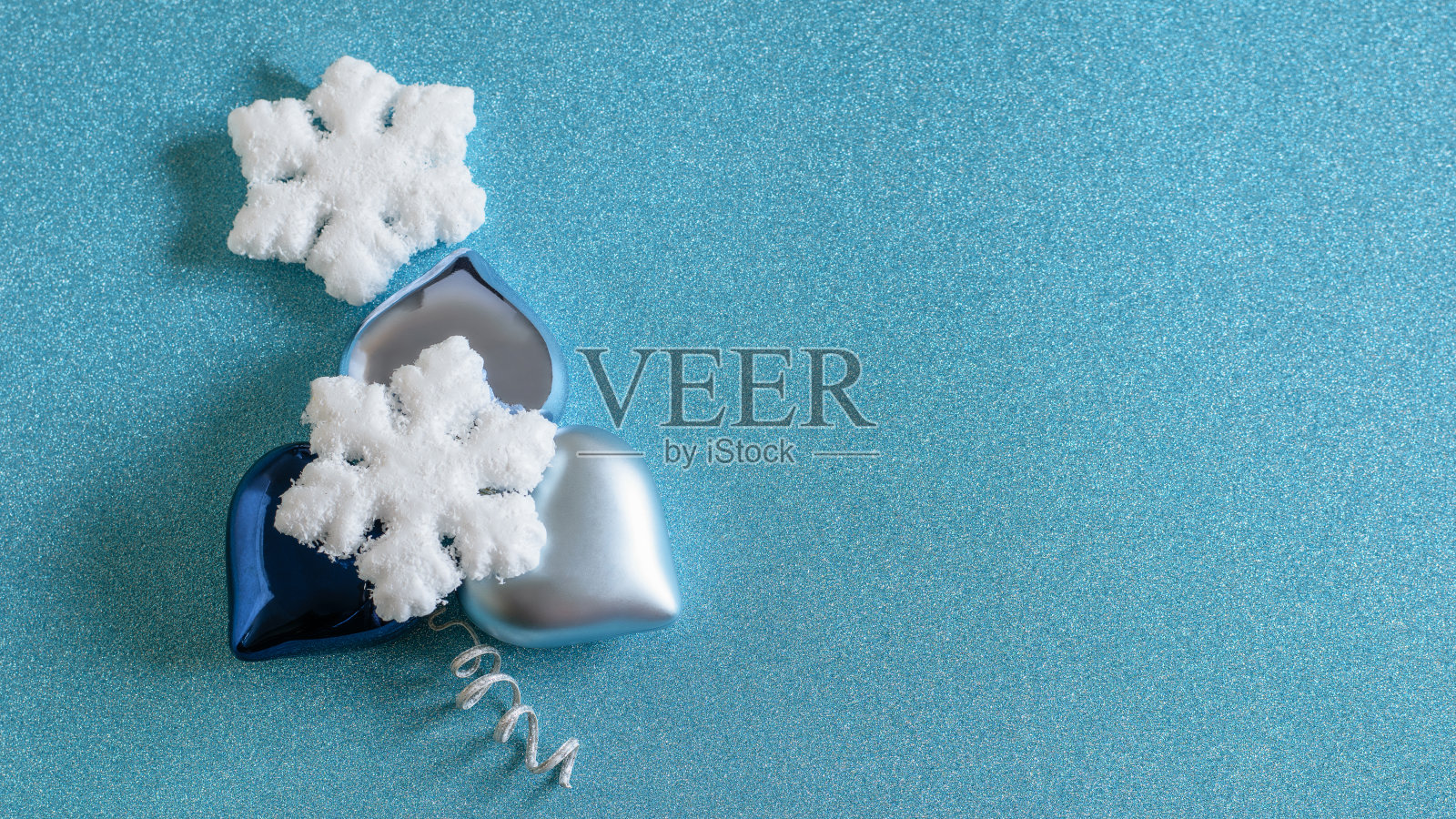 在水蓝色的圣诞背景上，雪花和喜庆的心形装饰品。照片摄影图片