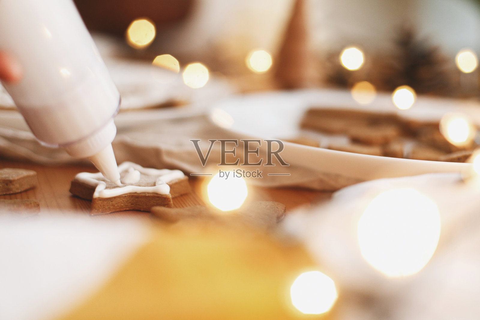 用糖霜装饰姜饼星形饼干在桌上用灯装饰。圣诞节的传统照片摄影图片