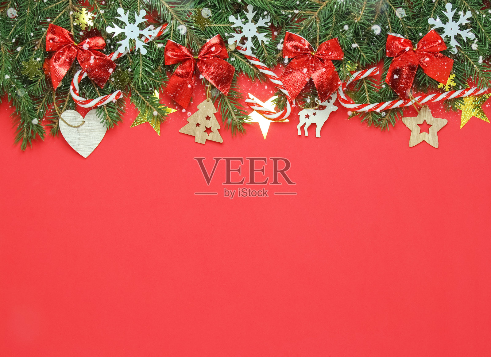 圣诞节的横幅用冷杉树枝，红色的弓，木制的装饰在红色的背景。贺卡框架，文字空间，俯视图，平面lay照片摄影图片