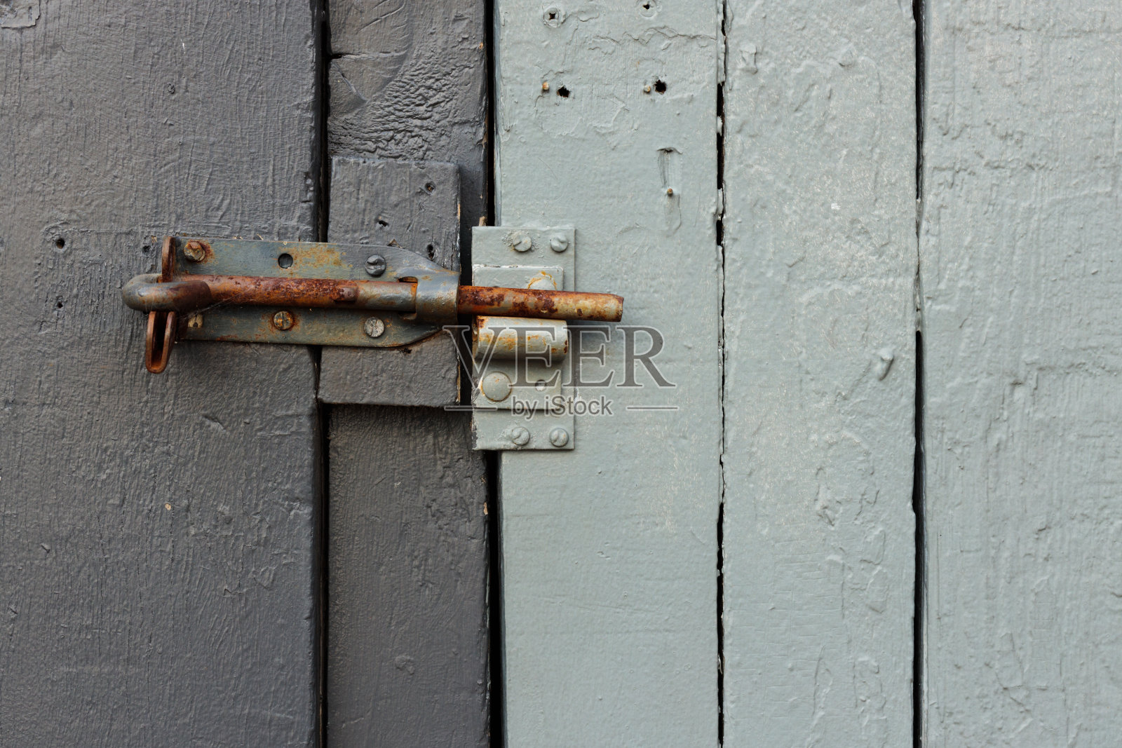 灰色木门上的生锈的铁栓。照片摄影图片