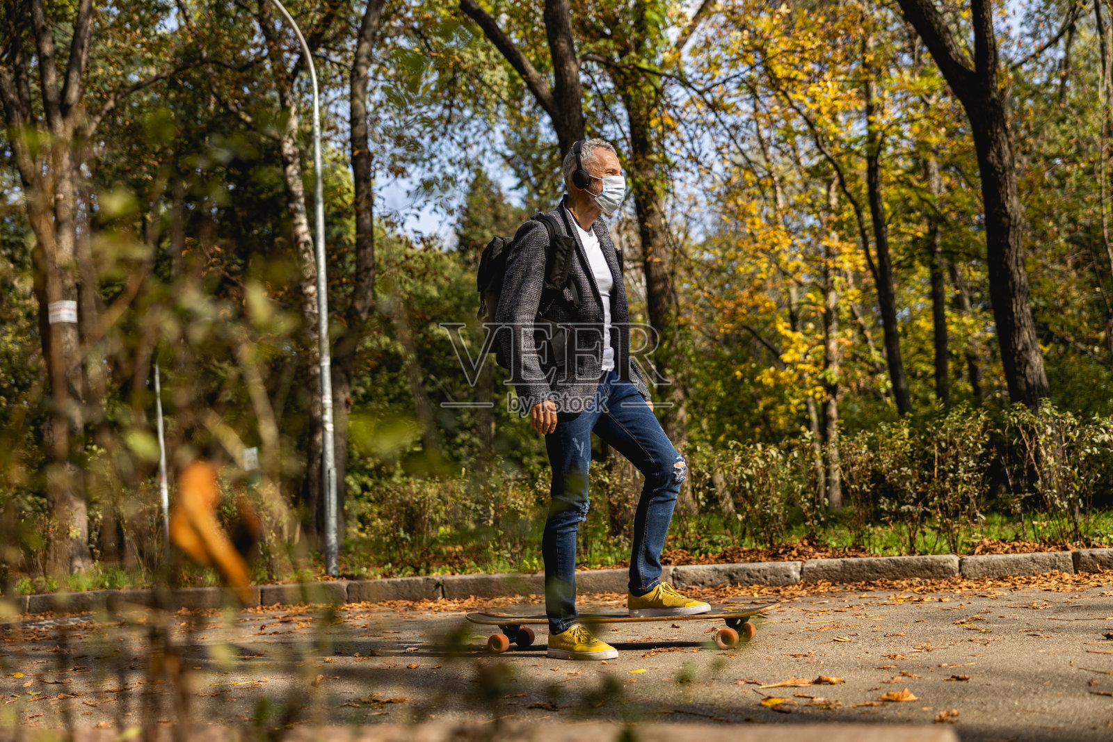 一个戴着面具的头发花白的帅哥在户外玩滑板照片摄影图片