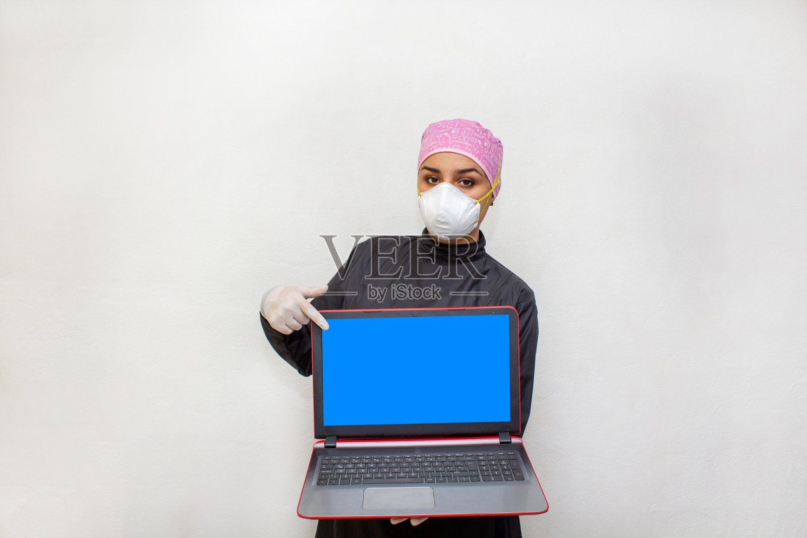 女医生或牙医穿着手术服和n95口罩显示笔记本电脑屏幕照片摄影图片