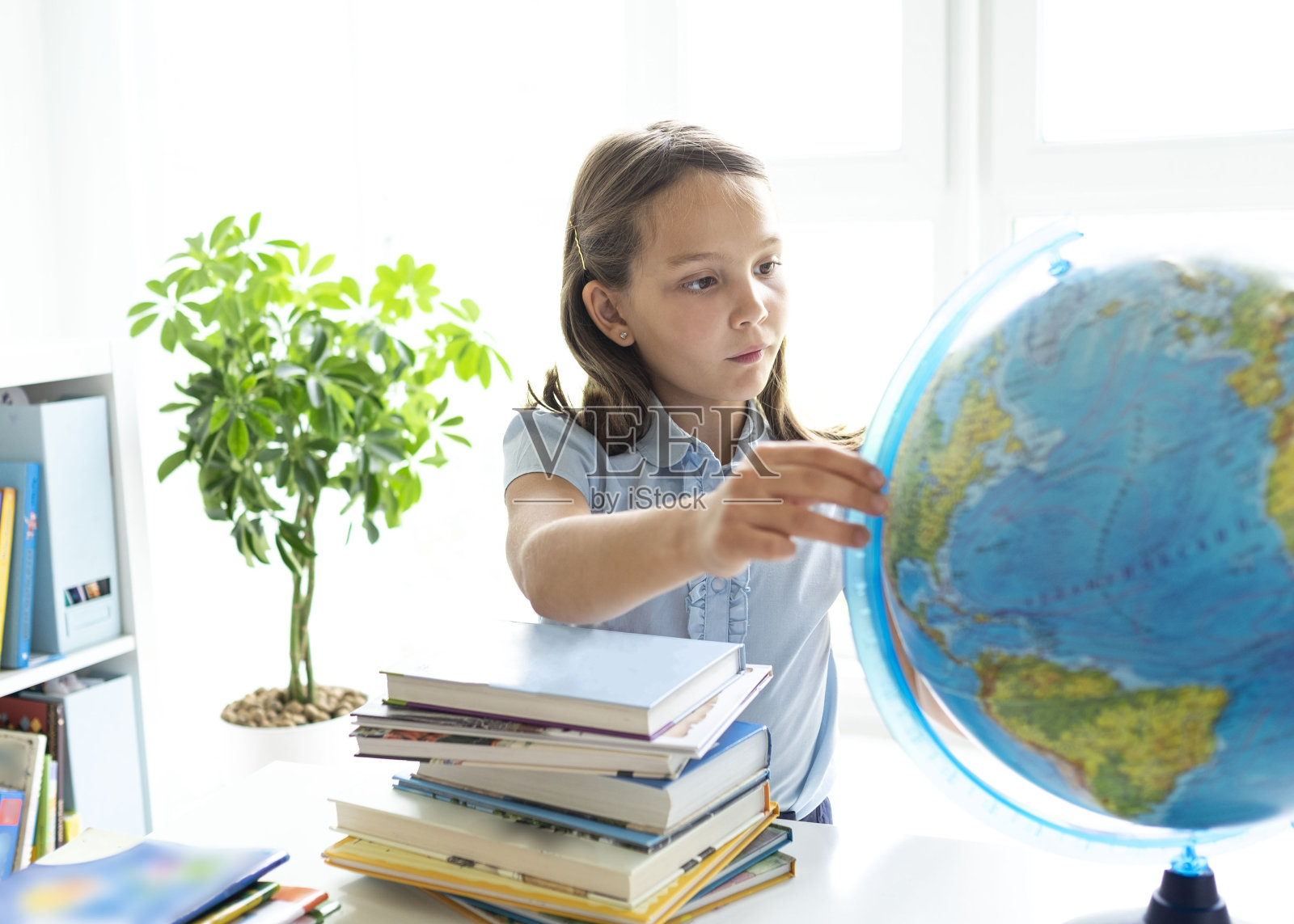 微笑的白人女孩坐在课桌上看着练习册。年轻女学生在学校学习的肖像。非常聪明的小学生在笔记本上写字。照片摄影图片