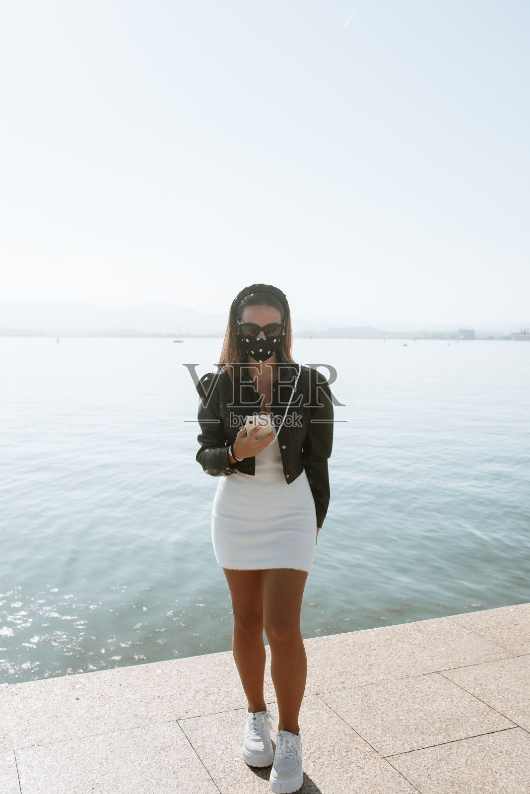 年轻女子戴着防护面罩使用智能手机照片摄影图片