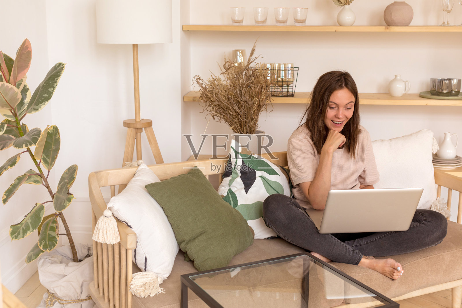 在沙发上使用笔记本电脑的快乐女人照片摄影图片