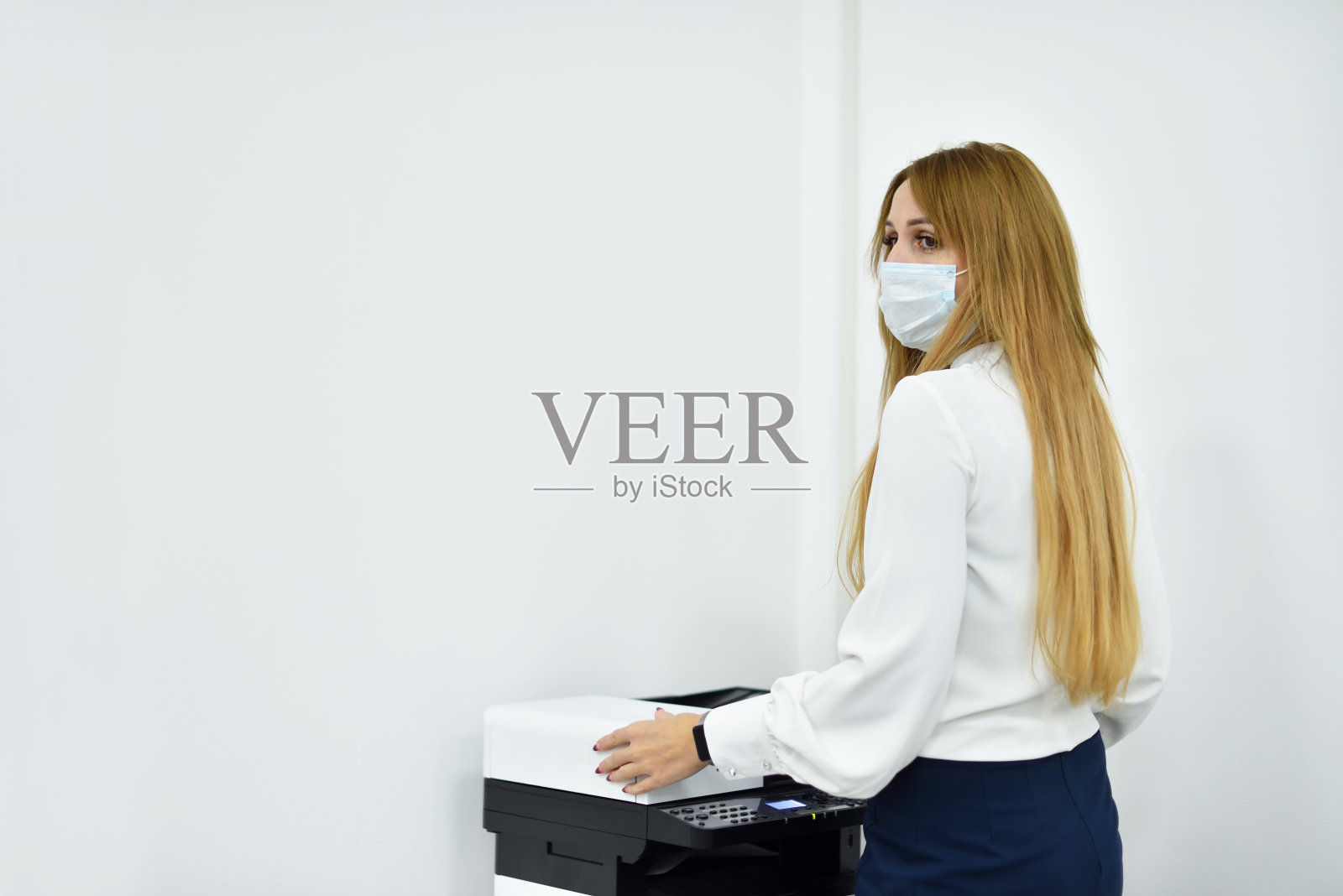 30多岁的女办公室经理戴着面具在复印机上复印文件照片摄影图片