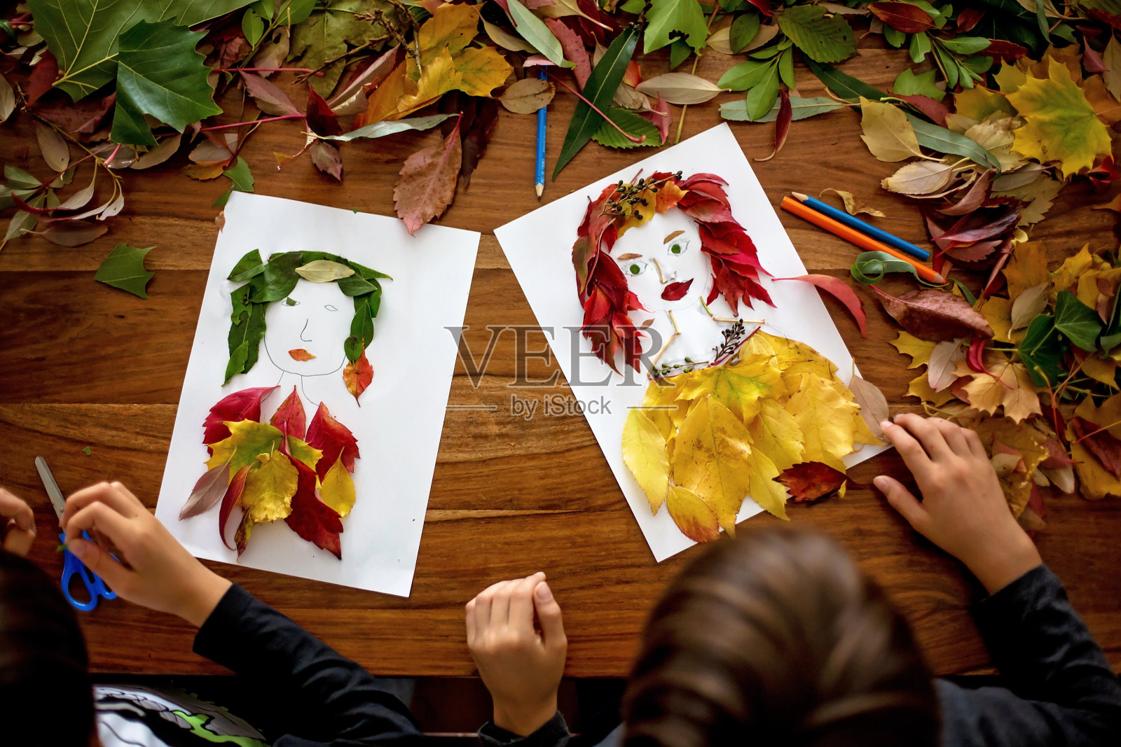 孩子，在客厅用树叶做女人肖像，用胶水涂树叶照片摄影图片