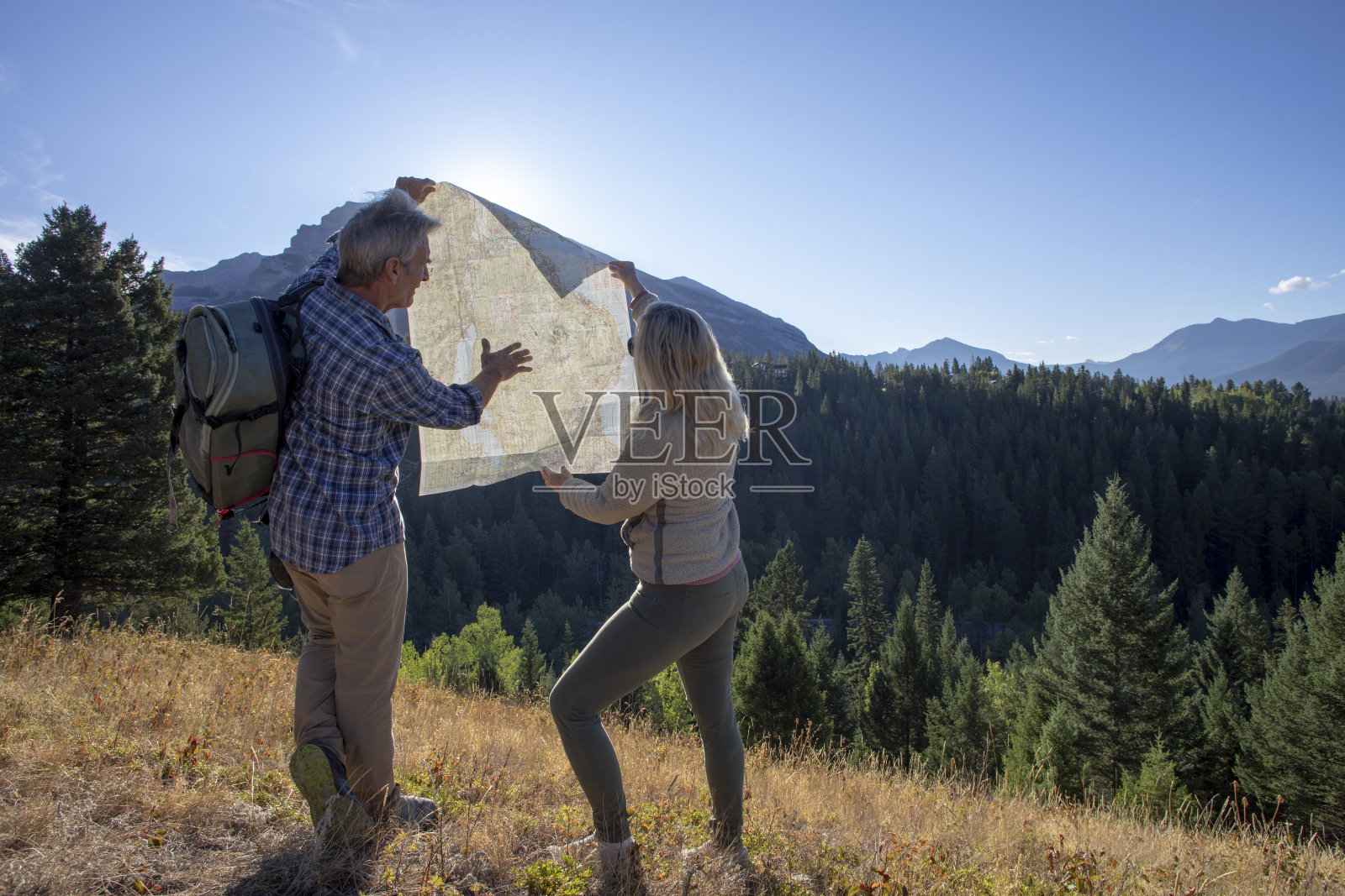 日出时，徒步旅行的夫妇在草地上休息照片摄影图片