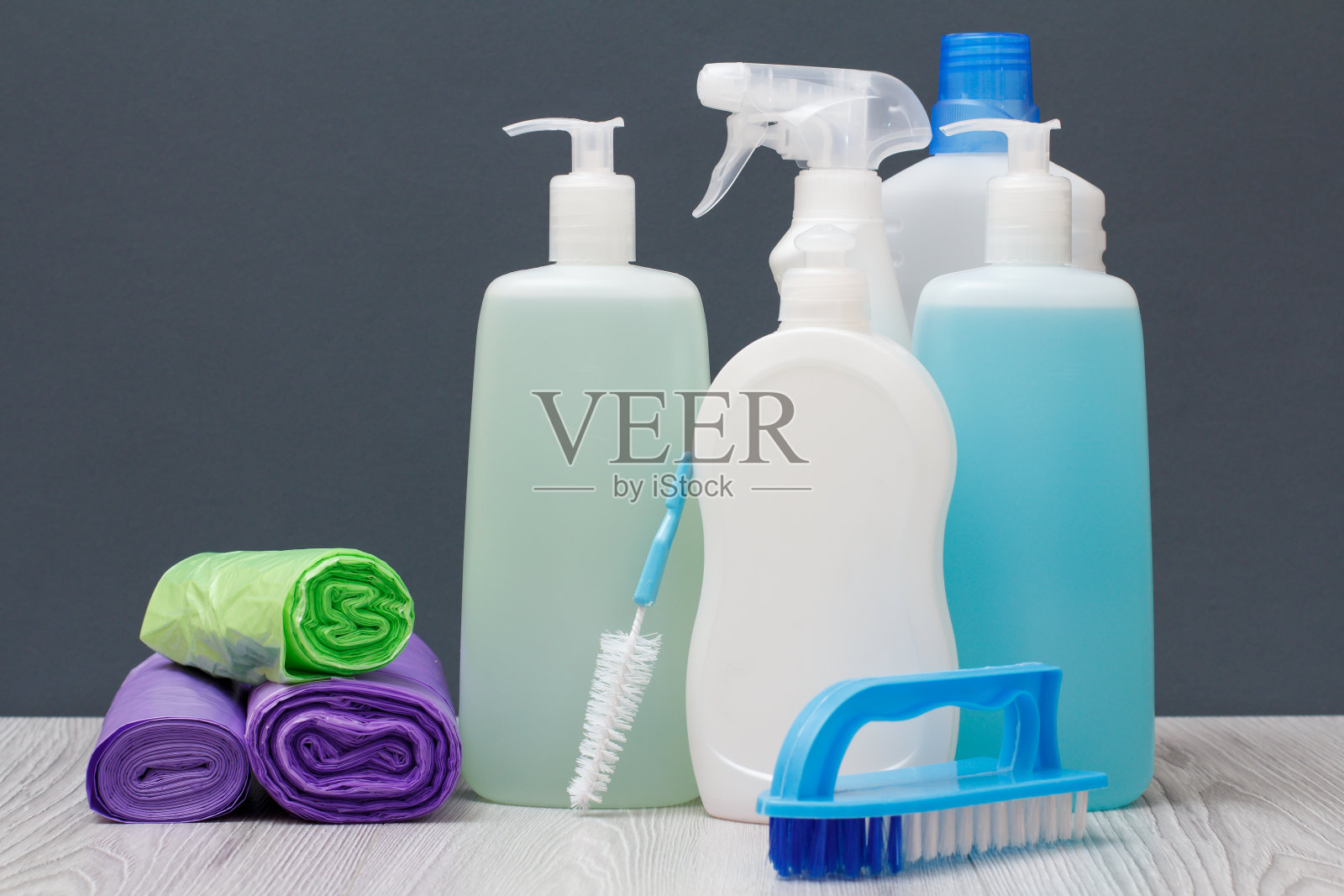灰色背景上有洗洁精、刷子和垃圾袋。照片摄影图片