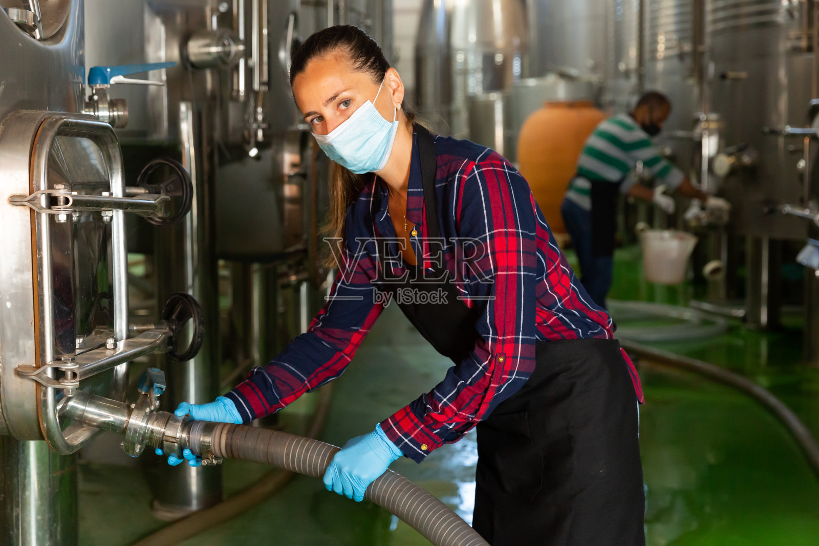 女工人在酿酒厂工作，在桶中过滤葡萄酒照片摄影图片