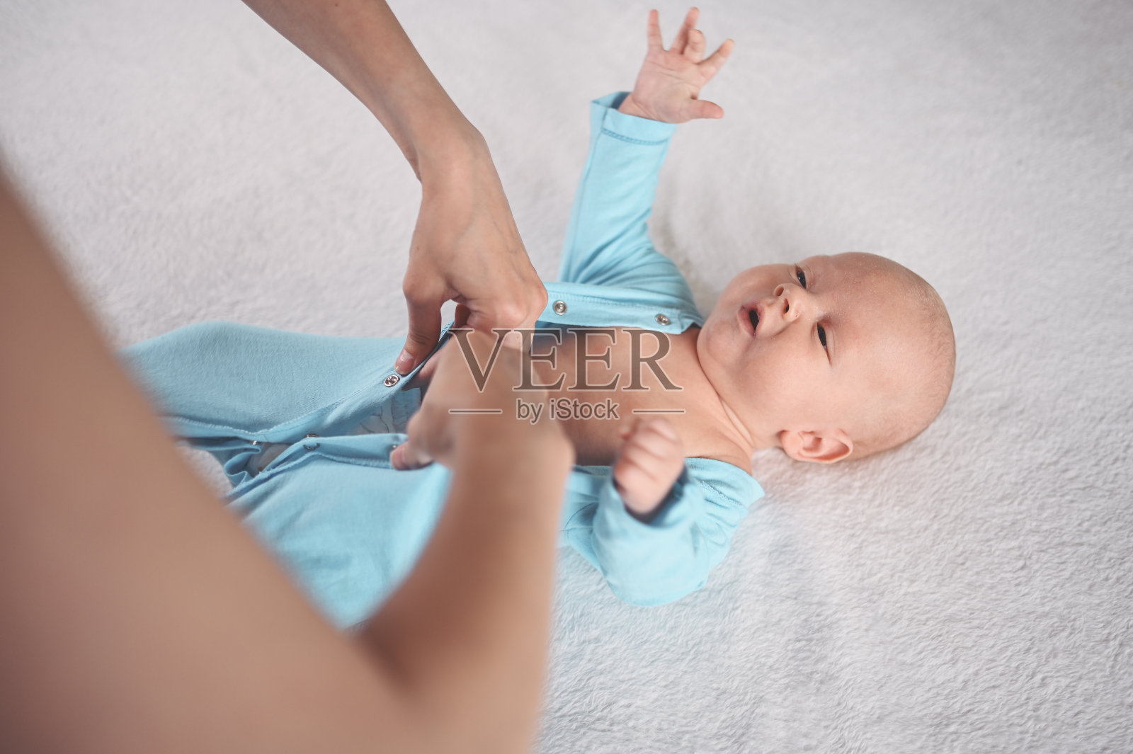 妈妈穿着可爱的、感性的、有趣的、新生的小婴儿宝宝的蓝色连衣裤照片摄影图片