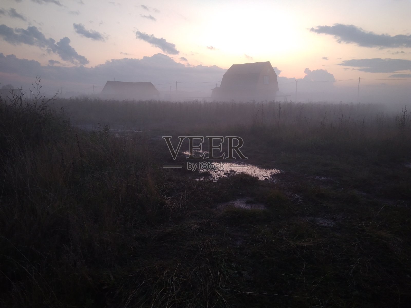 晨雾中房屋的剪影，笼罩着秋日草地上的田野照片摄影图片