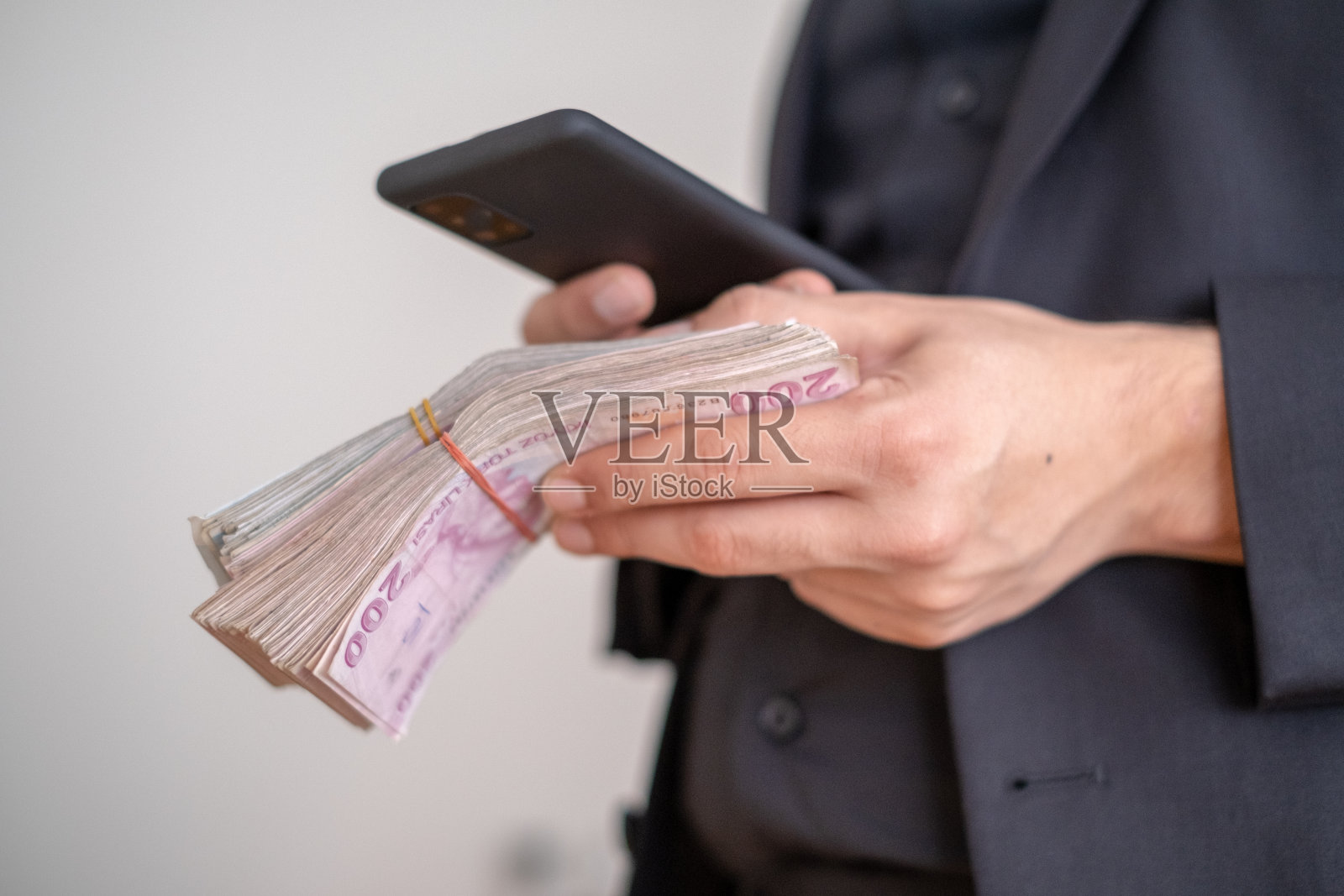 用手机，手里拿着钱。照片摄影图片