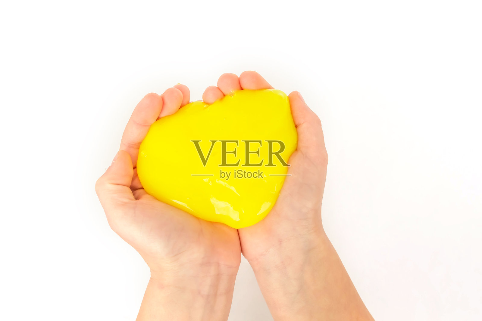 现代玩具叫做黏液。孩子玩透明的黄色黏液。双手拿着一个粘液在白色的背景。有选择性的重点。照片摄影图片