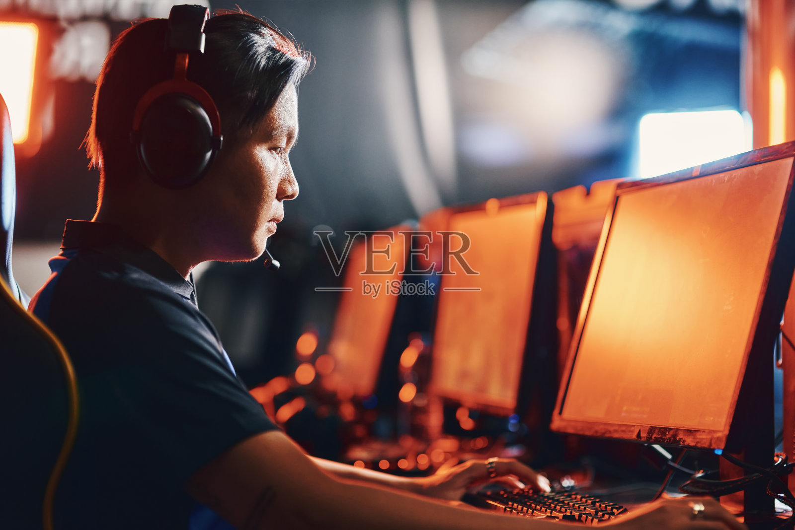 男性职业电子竞技玩家戴着耳机玩网络游戏，参加电子竞技比赛照片摄影图片