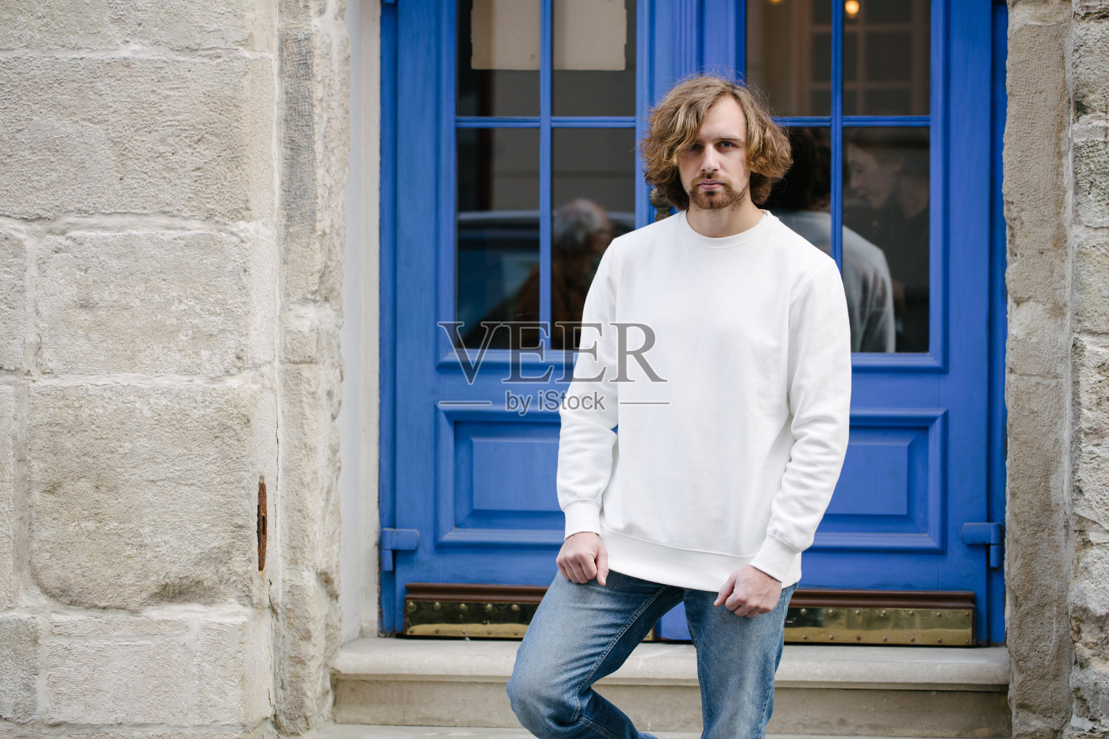 穿着白色运动衫或帽衫的男子模拟，标志设计或设计印花与城市街道上的自由空间。照片摄影图片