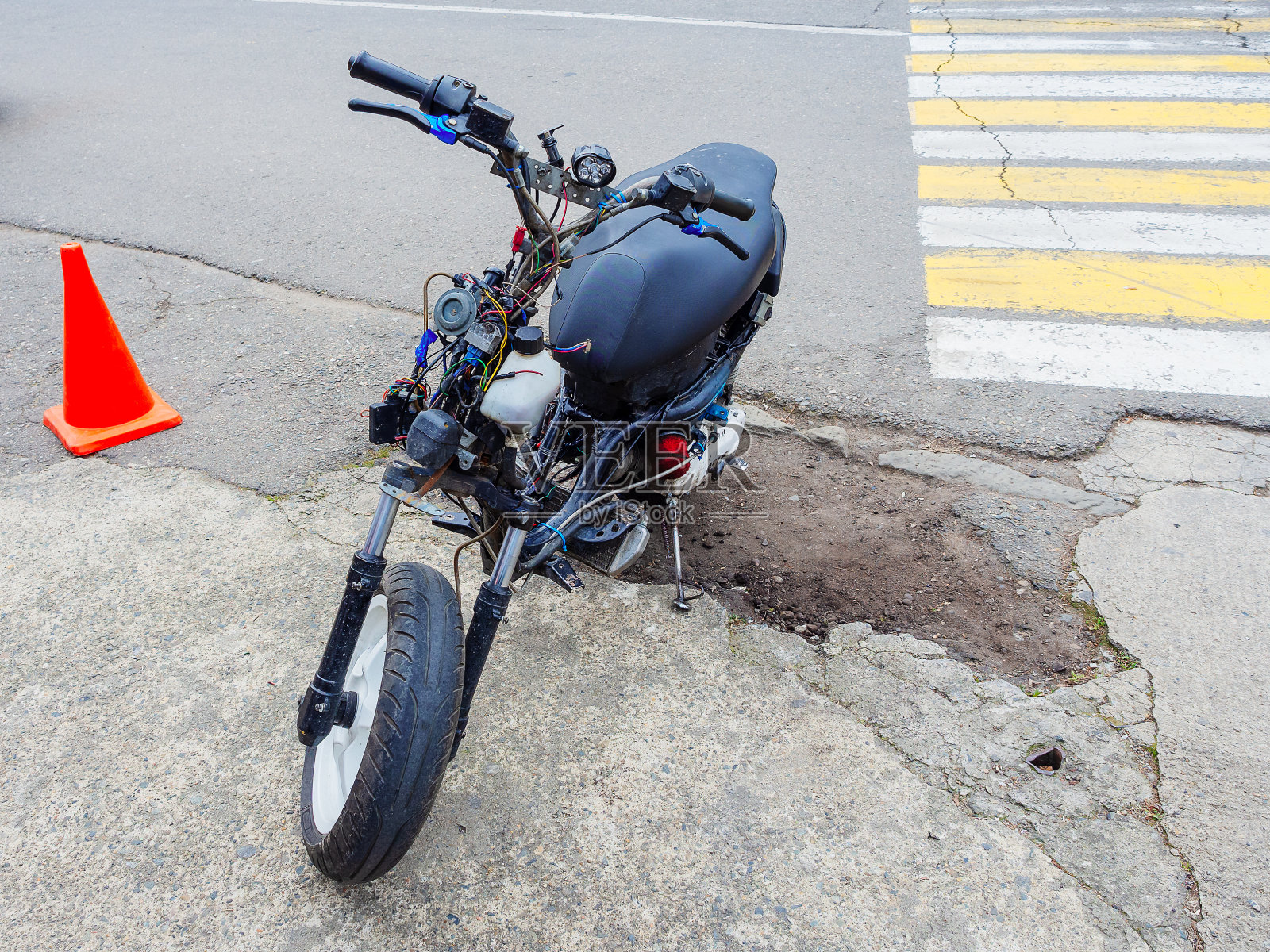 一辆半拆卸的、电线伸出来的助力车停在柏油路边照片摄影图片