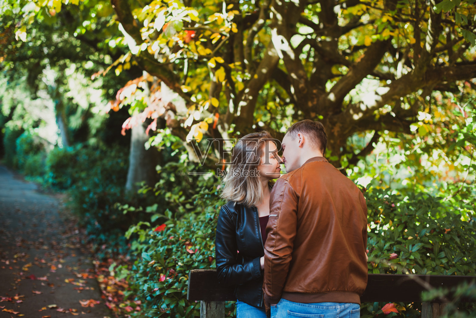 年轻的白种情侣在大自然中享受幸福的时刻。这个年轻人在秋天的公园里浪漫的约会中拥抱了他的女朋友。秋天的心情。有选择性的重点。副本的空间。照片摄影图片