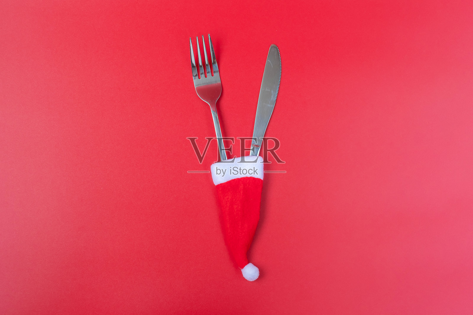 红色背景上的圣诞老人、餐叉和勺子：圣诞、派对和新年概念照片摄影图片