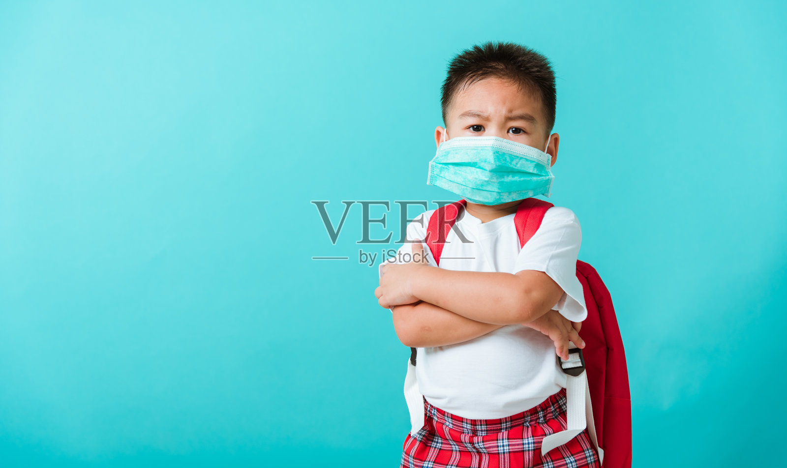 孩子上幼儿园前戴好防护口罩和书包照片摄影图片