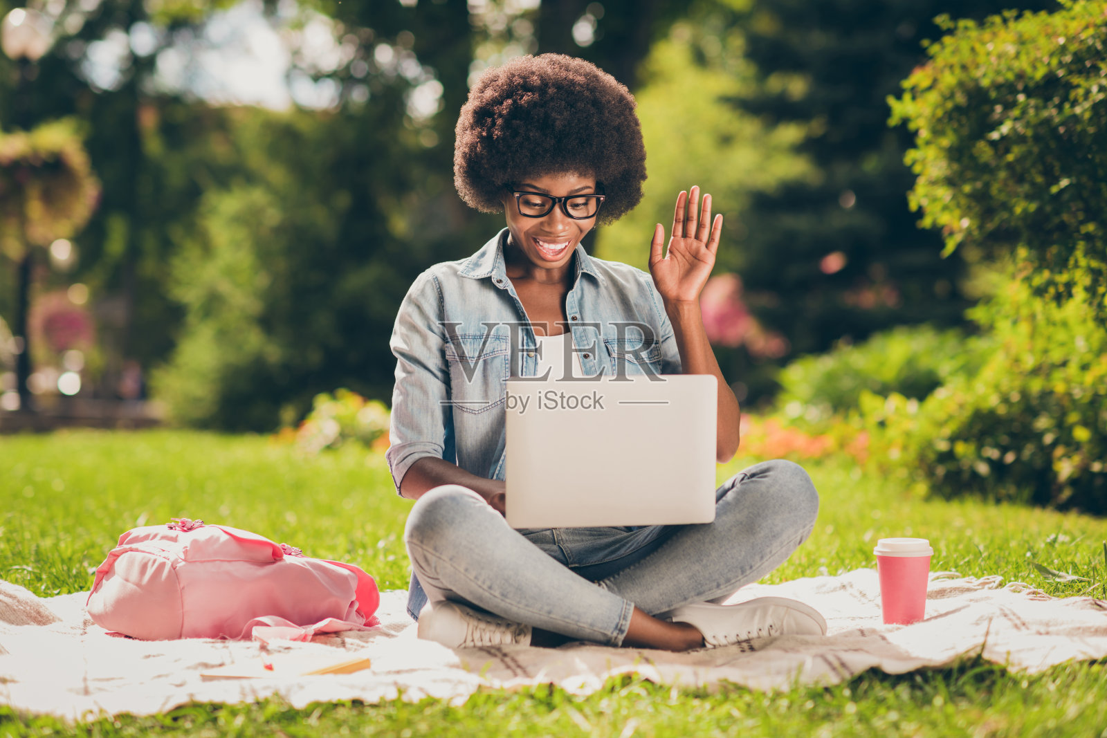 照片肖像的黑人女孩看喜剧电影大声笑着笔记本电脑坐在公园戴眼镜照片摄影图片
