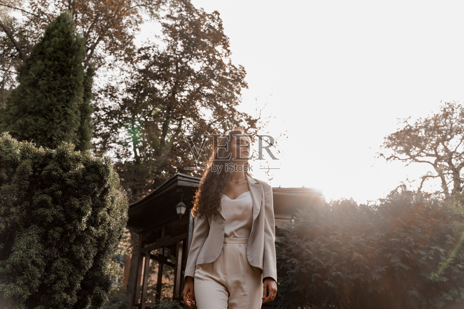 在绿色的公园里的微笑女孩。快乐的年轻女子绕着绿色的花园散步。年轻女商人的生活方式。照片摄影图片