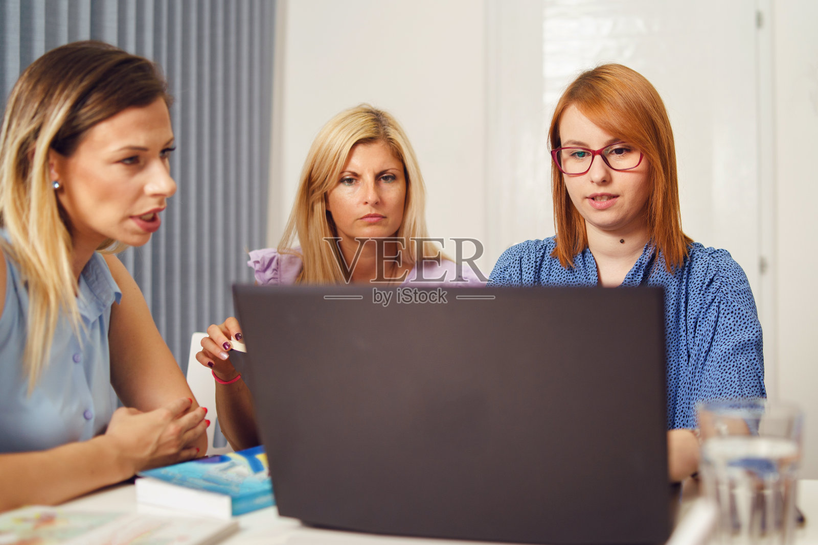 一群女性同事坐在办公室里用笔记本电脑一起工作的项目-千禧一代的老板和企业家开会头脑风暴的概念照片摄影图片