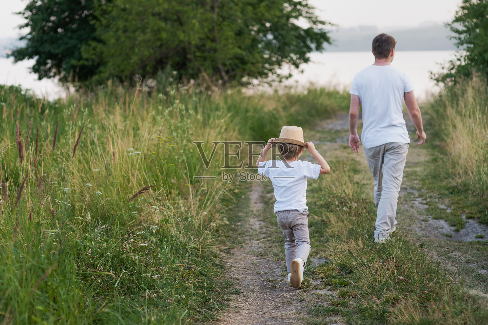 快乐的家庭，父亲和儿子在夏天一起漫步在草地上照片摄影图片